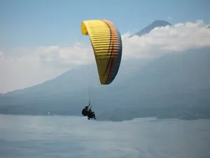 Gleitschirmflieger über dem Atitlán-See, mit einem Vulkan im Hintergrund; dargestellt auf der Tandemflug-Seite des Anbieters.